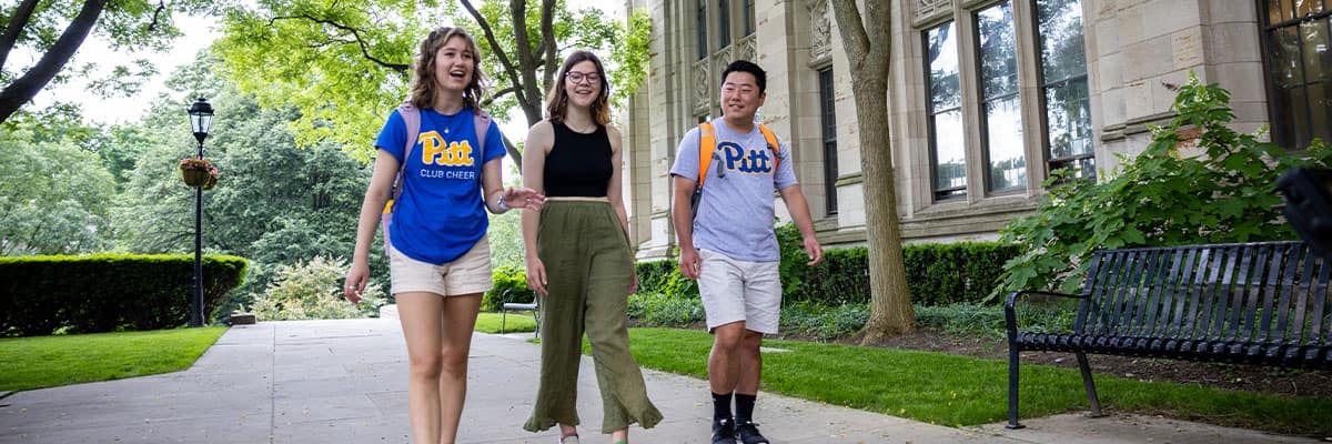Three students walking in Cathedral Courtyard.